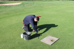 Greenkeeper cutting a hole